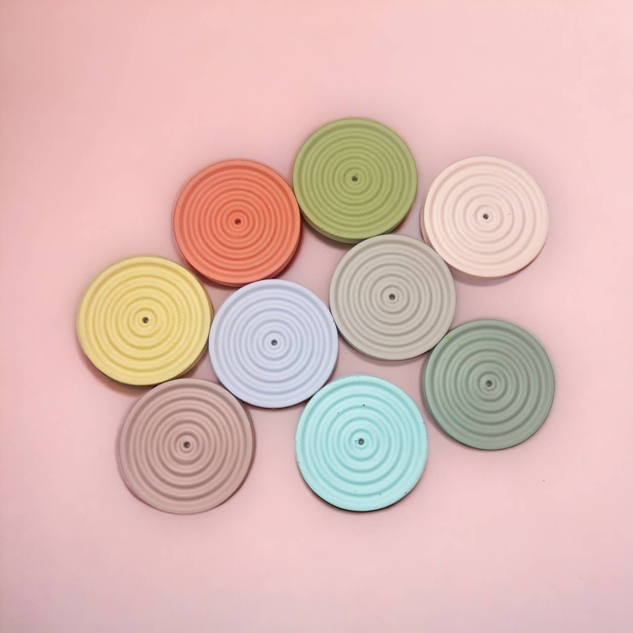 Assorted ripple-textured concrete incense holders in bright colors, displayed in a circular layout with incense sticks resting in the center grooves.