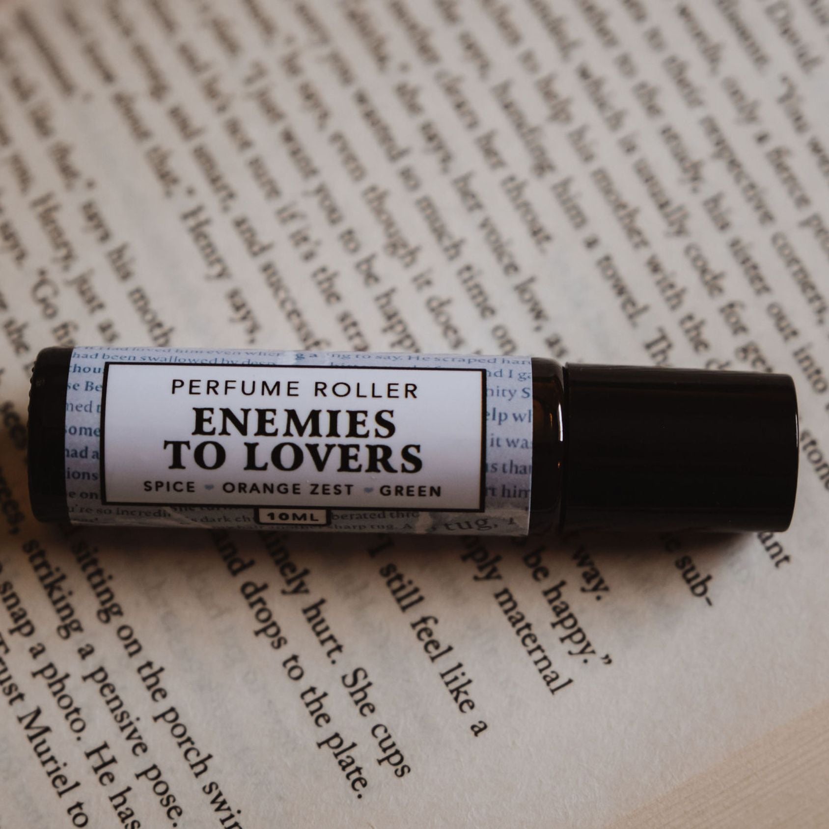 “Enemies to Lovers” roller resting on a romance book page, with handwritten annotations visible.