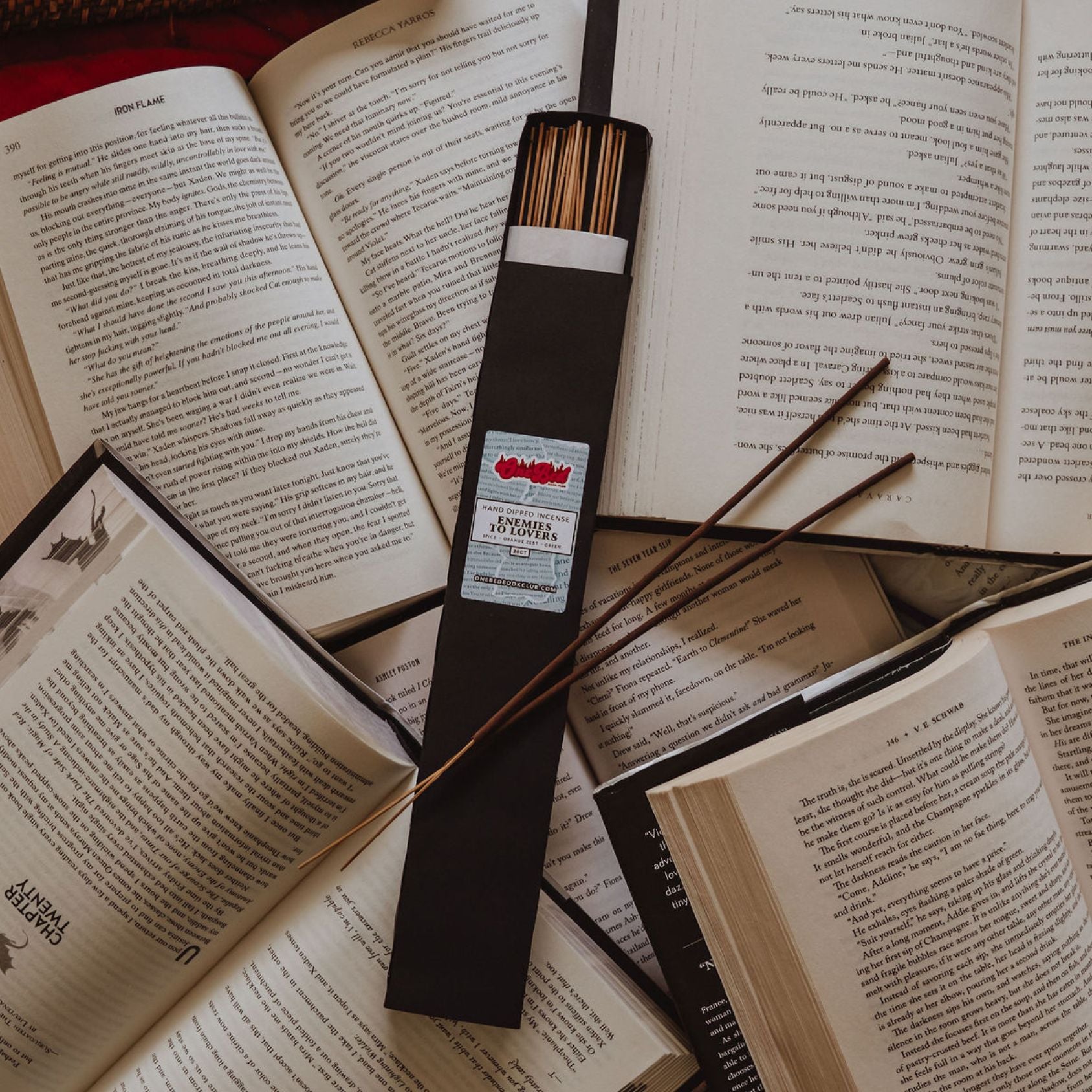 Single incense bundle in focus on open book pages with black and white text background.