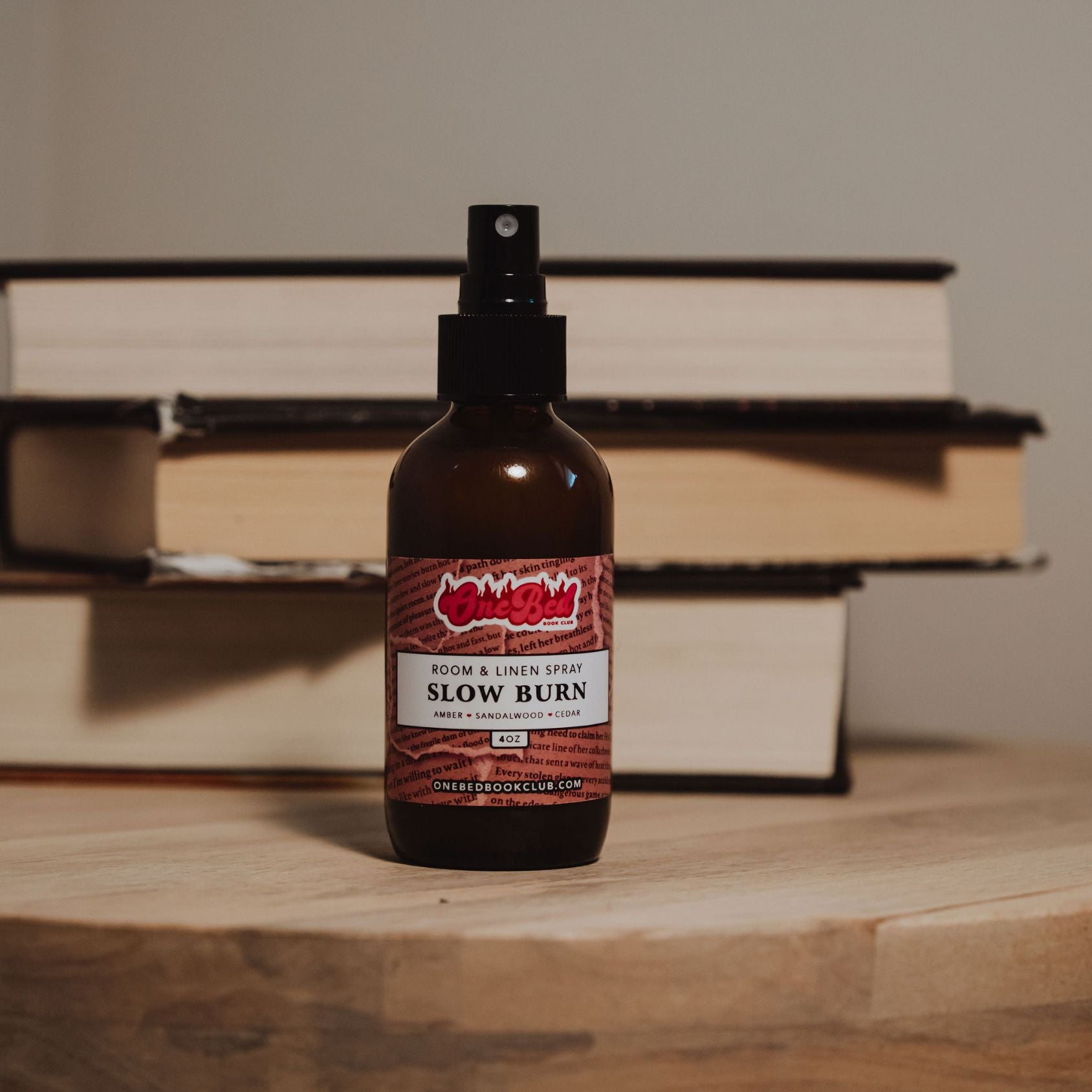 Close-up of One Bed Room Spray bottle titled “Slow Burn” nestled among books