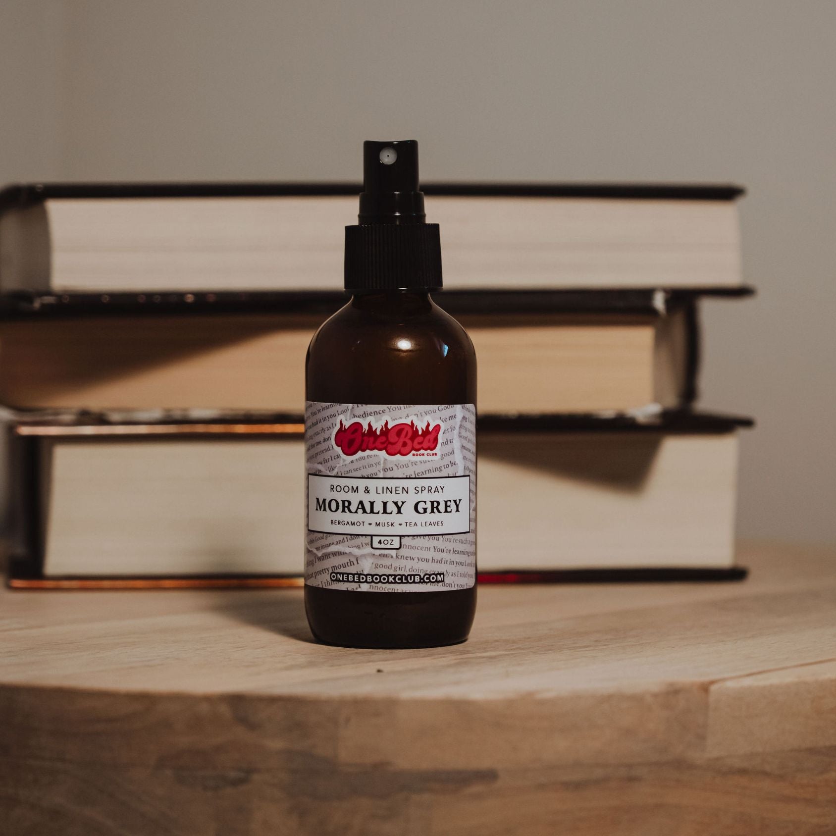 Room spray bottle in focus with open book pages blurred in the background with label showing "morally grey"