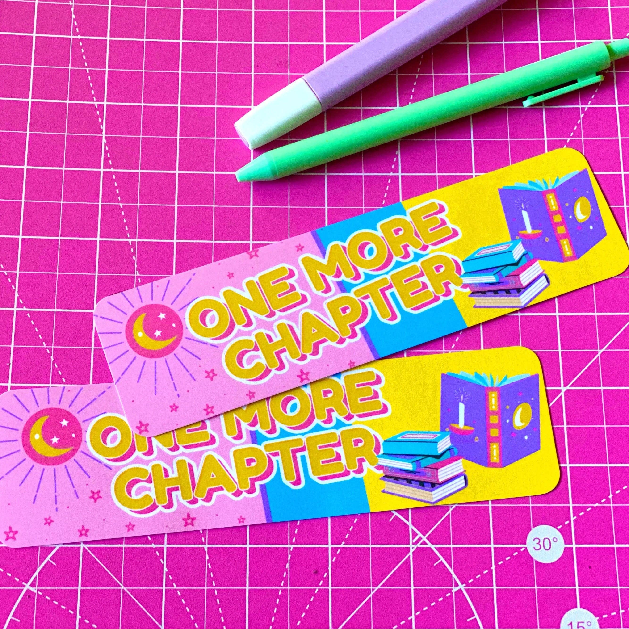 Two bookmarks with 'One More Chapter' text on a pink grid background