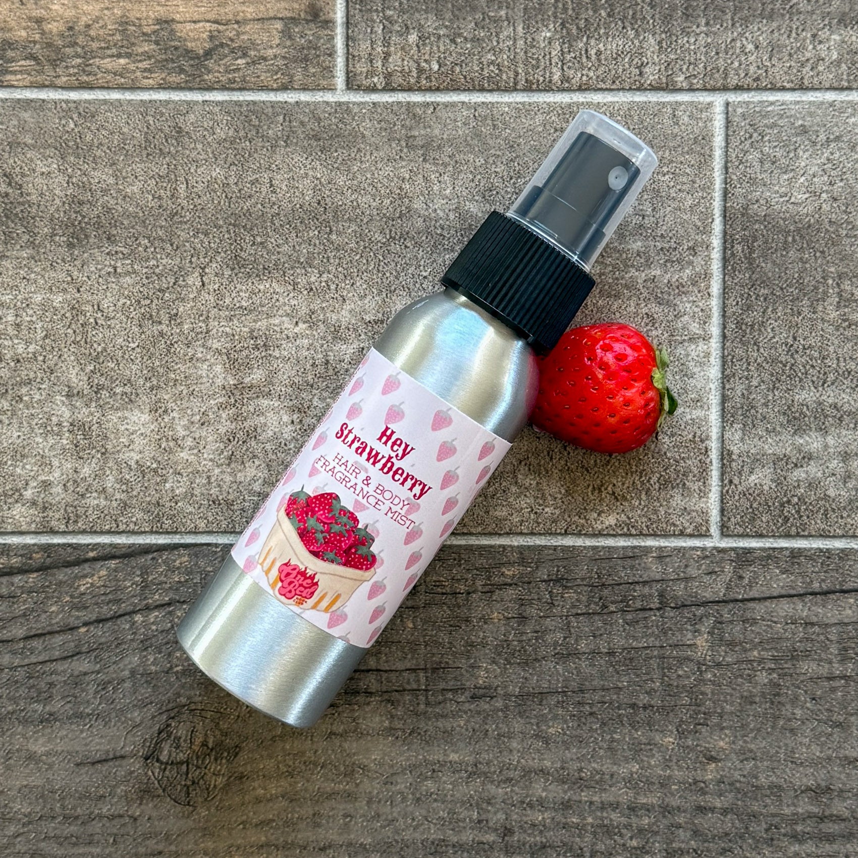 Aluminum bottle labeled “Hey Strawberry” with pink heart pattern and a strawberry beside it. Romance merch inspired by Holly Renee.