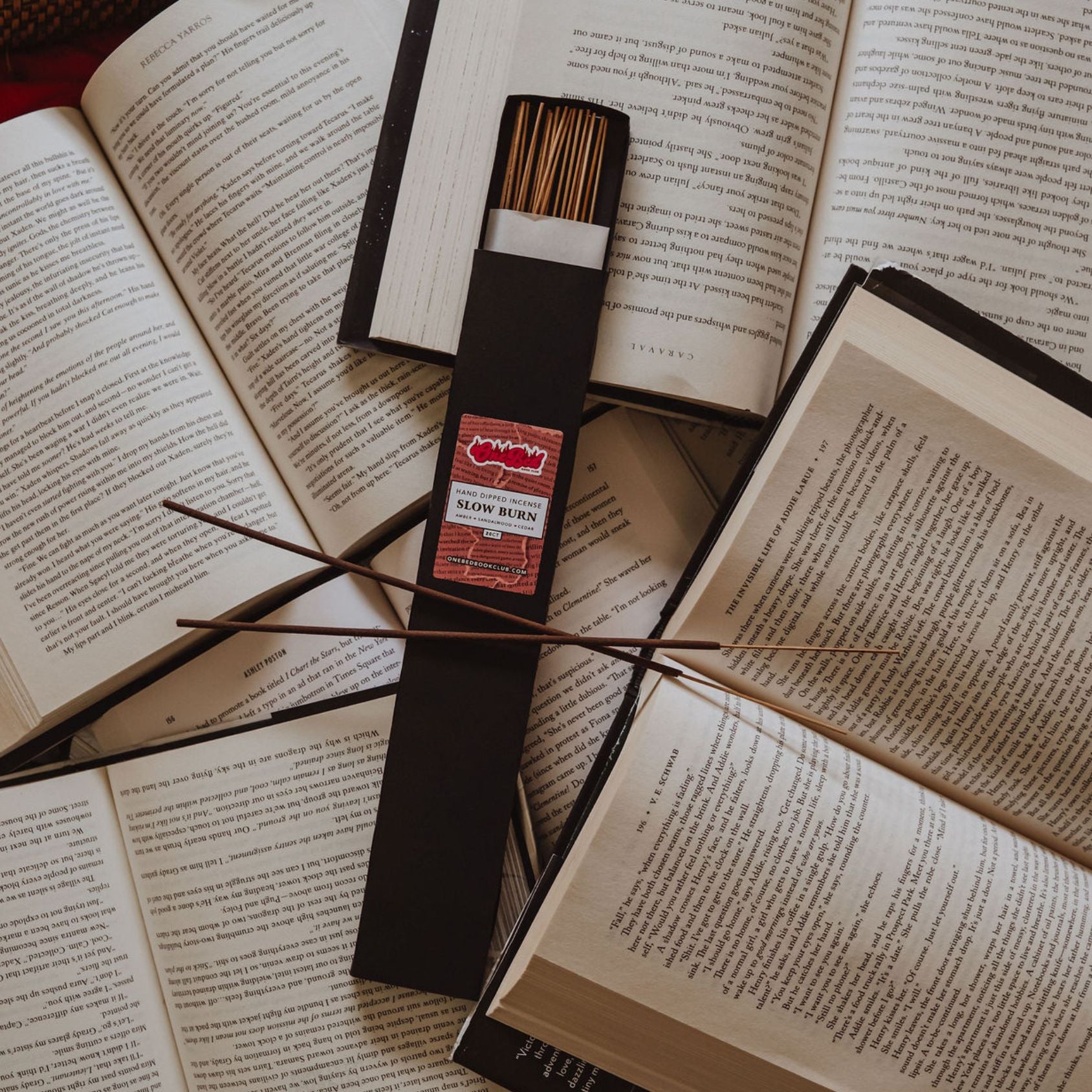 Close-up of  incense bundle wrapped with One Bed labels, laid on open book pages.
