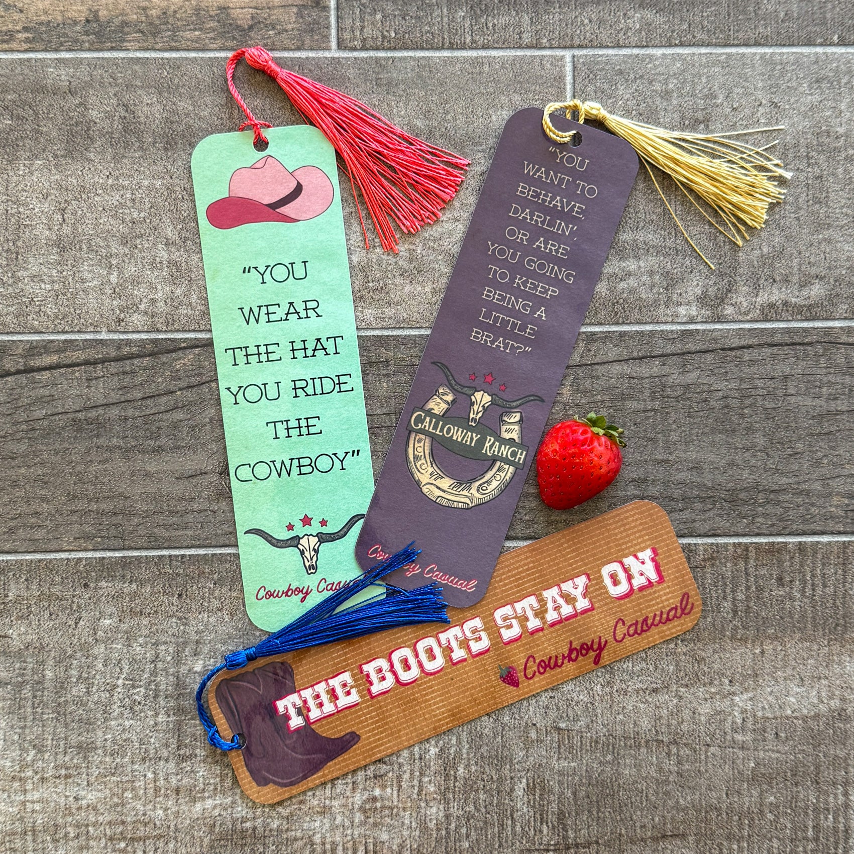 Three spicy romance bookmarks with quotes from Cowboy Casual by Holly Renee, featuring cowboy hats, western colors, and tassels