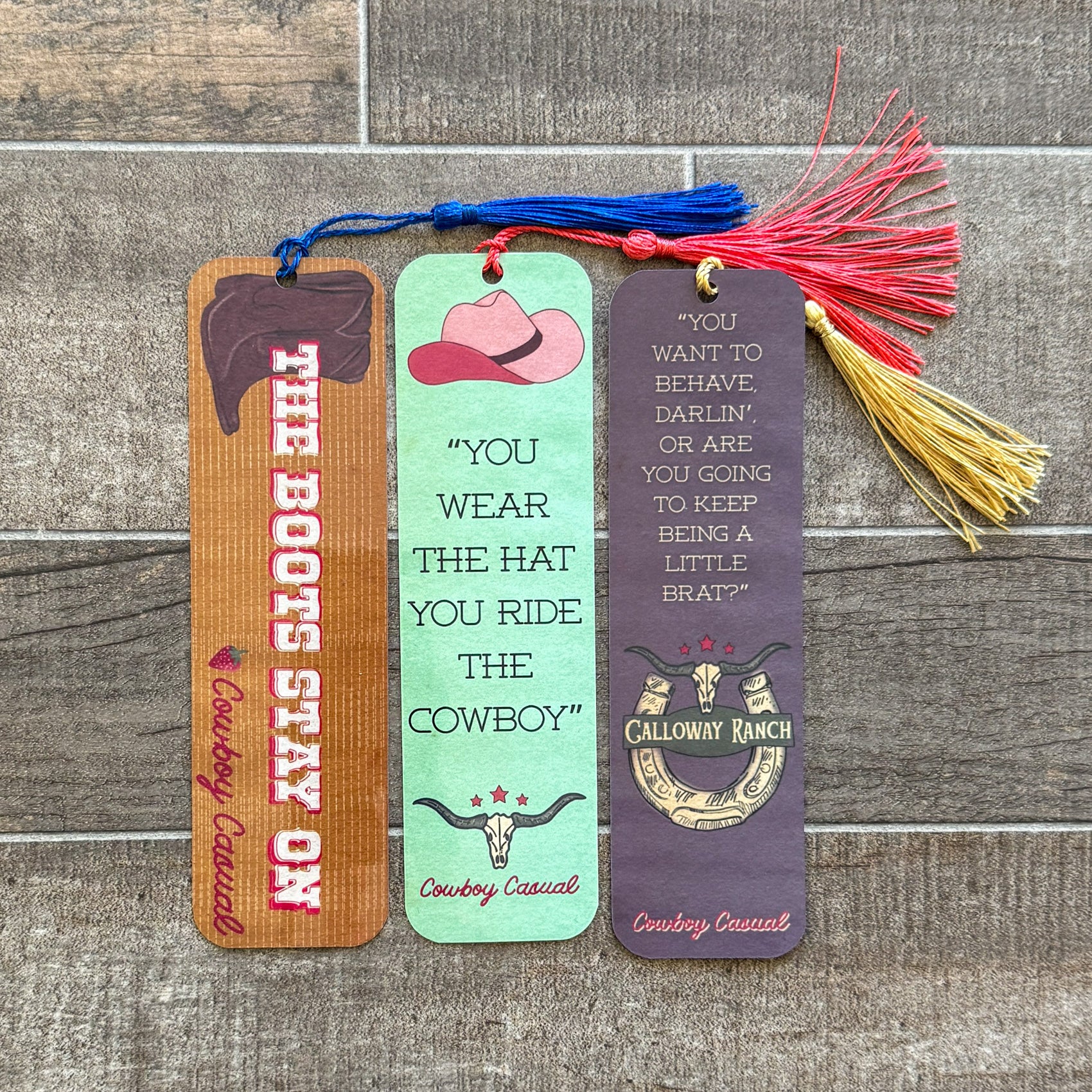 Three spicy romance bookmarks with quotes from Cowboy Casual by Holly Renee, featuring cowboy hats, western colors, and tassels