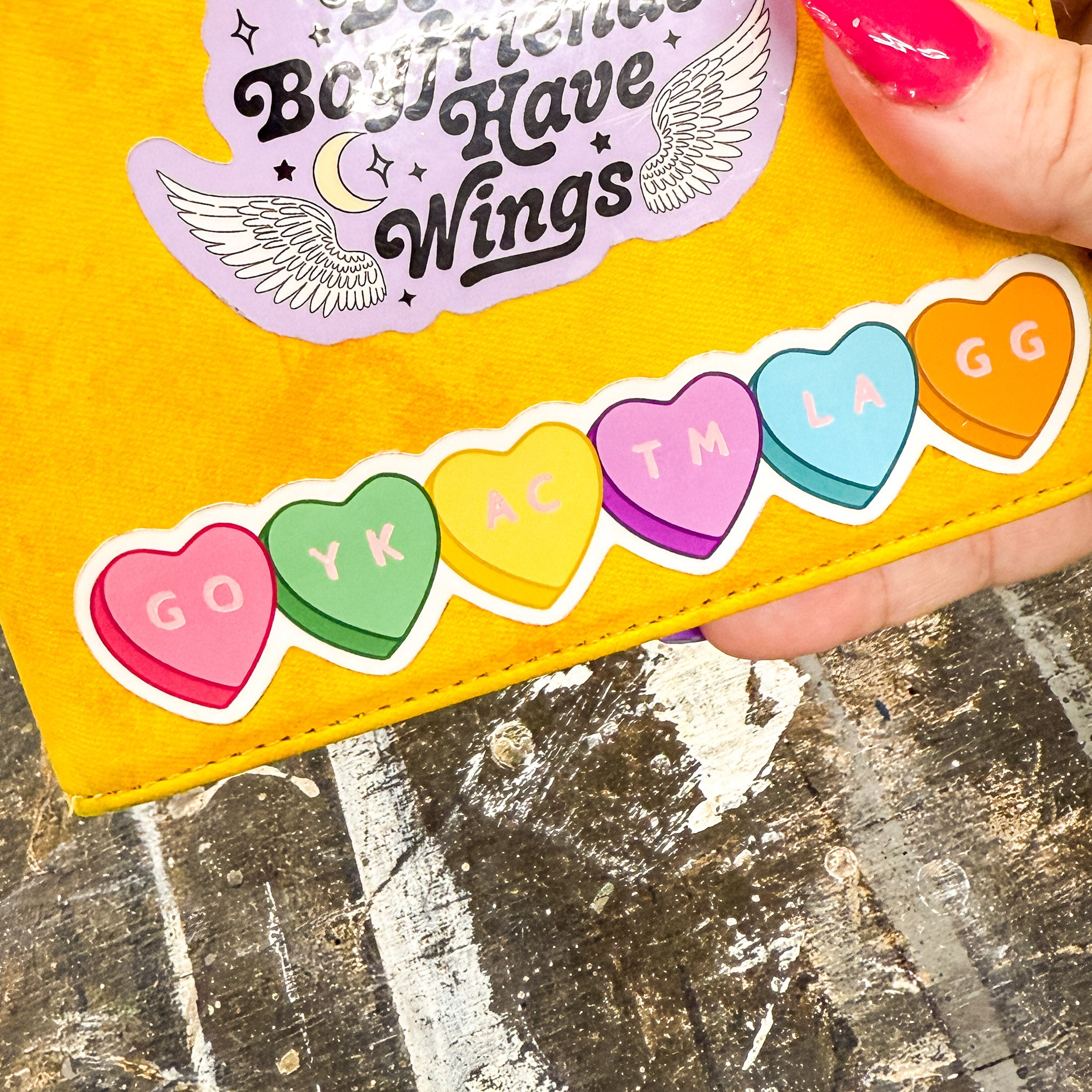 Vinyl sticker of colorful candy hearts with bookish abbreviation NSFW shown on a yellow kindle case 